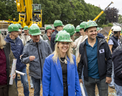 Blije aanwezigen met groene bouwhelmen tijdens viering start bouw wijk Griseeweg